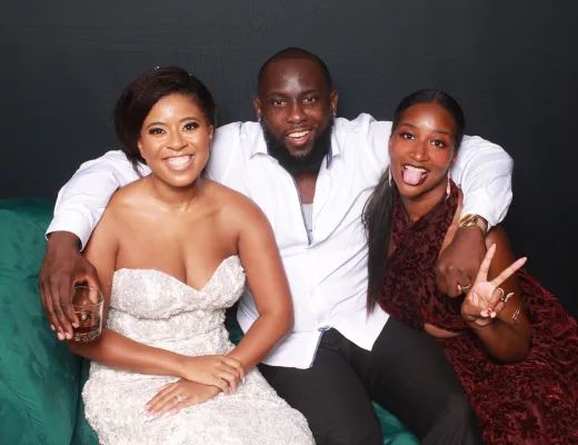Three guests laughing together on a green velvet couch at a staged event photo op