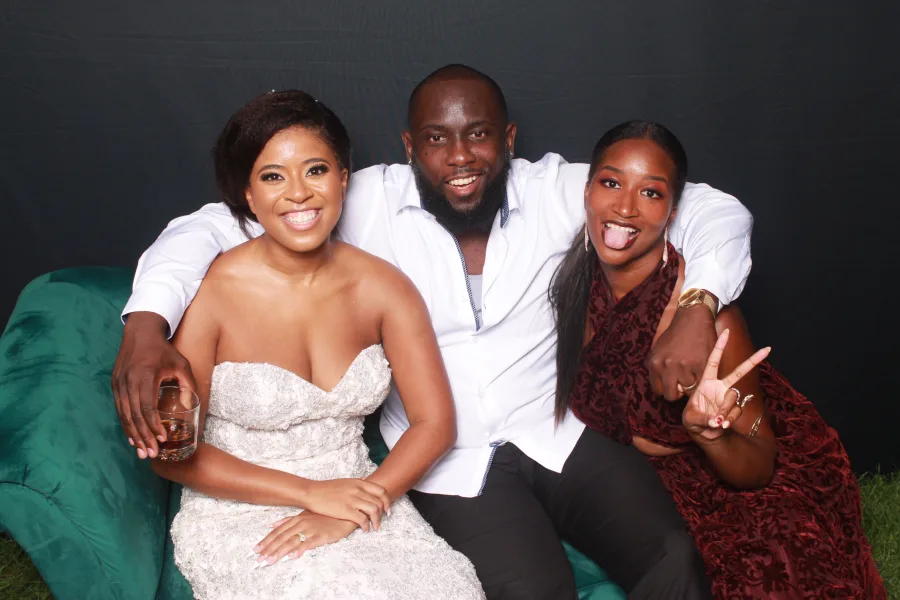 Three guests laughing together on a green velvet couch at a staged event photo op