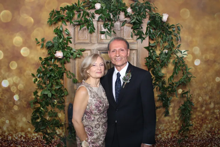 Older couple posing in front of a floral backdrop