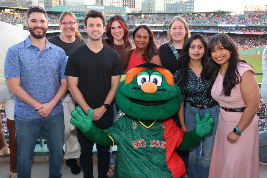 Corporate group photographed with a team mascot at a staged photo op on a ballpark concourse