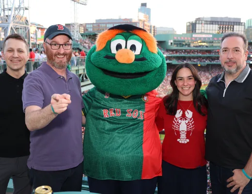Four guests photographed with a team mascot on the concourse at a ballpark