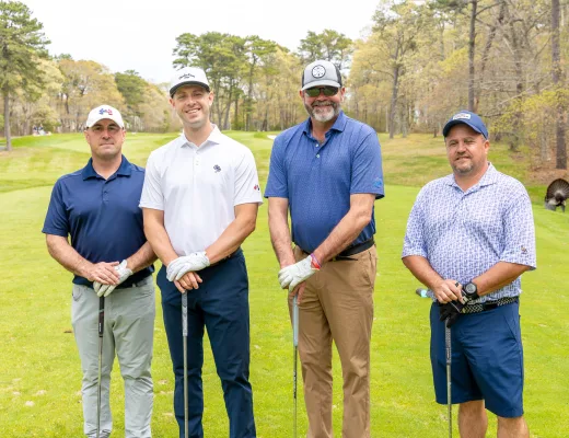 Golf tournament team photographed together with their clubs on the course
