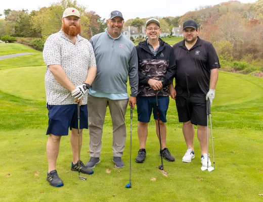 Golf tournament team photographed together with their clubs on the course