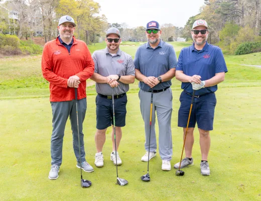 Golf tournament team photographed together with their clubs on the course
