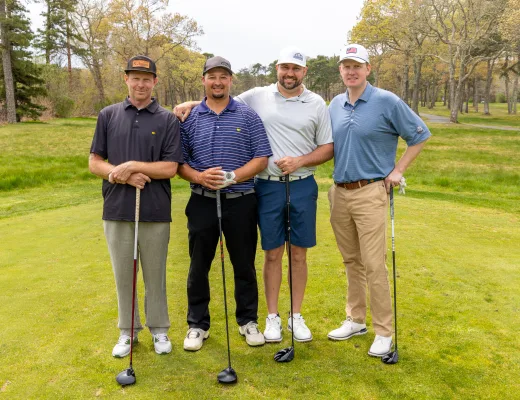 Golf tournament team photographed together with their clubs on the course