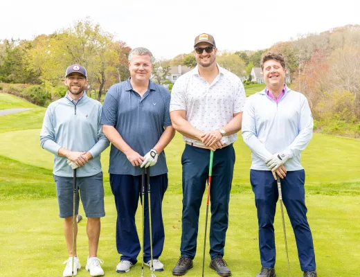 Golf tournament team photographed together with their clubs on the course