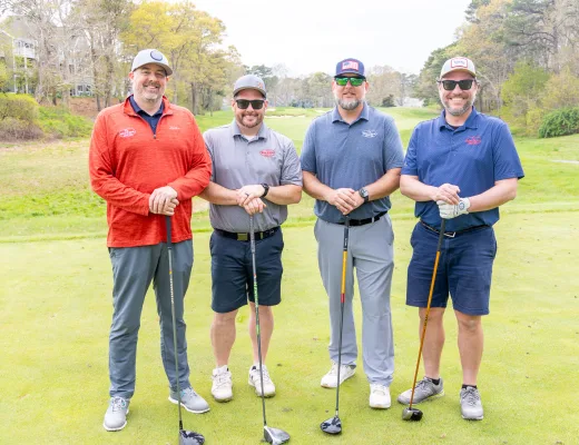 Golf tournament team photographed together with their clubs on the course
