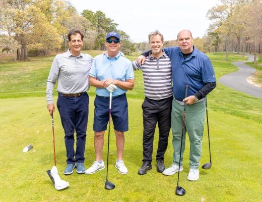 Golf tournament team photographed together with their clubs on the course