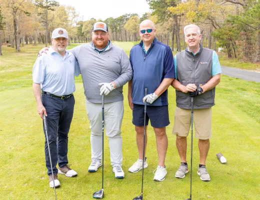 Golf tournament team photographed together with their clubs on the course