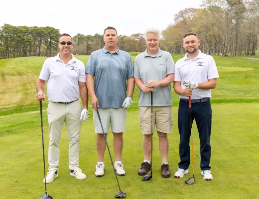 Golf tournament team photographed together with their clubs on the course