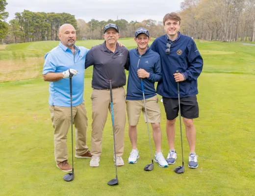 Golf tournament team photographed together with their clubs on the course