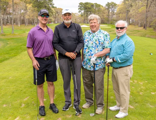 Golf tournament team photographed together with their clubs on the course