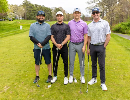 Golf tournament team photographed together with their clubs on the course