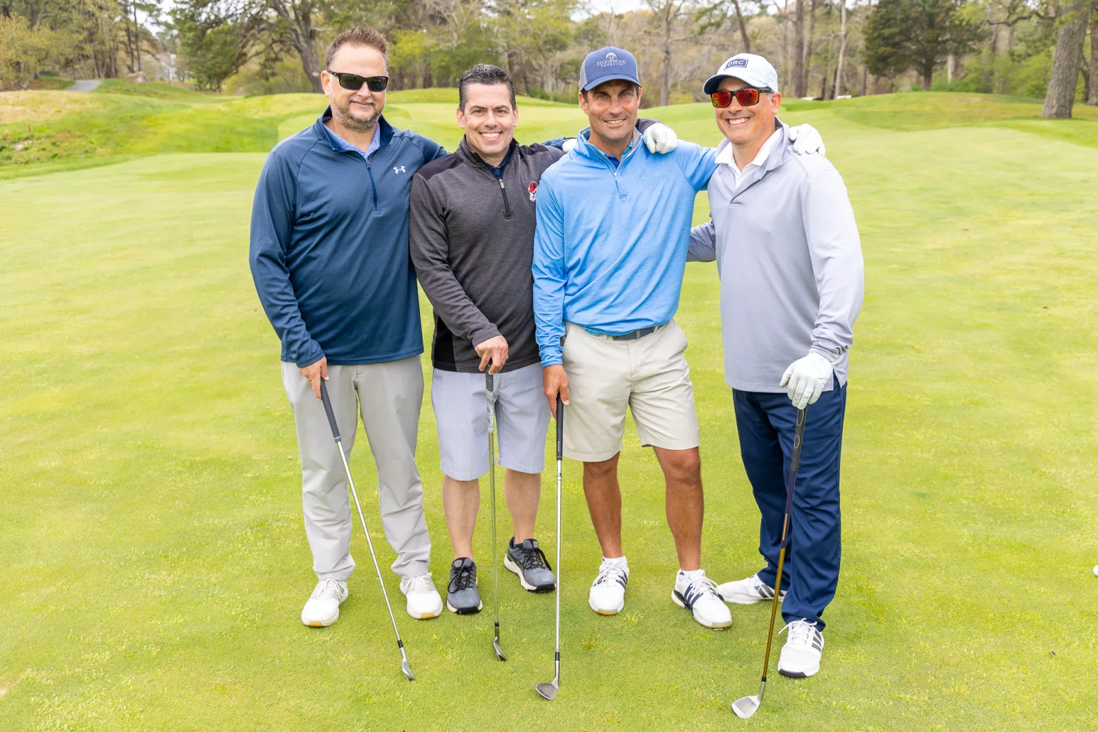 Foursome of golfers photographed together with their clubs on the tee at a golf tournament