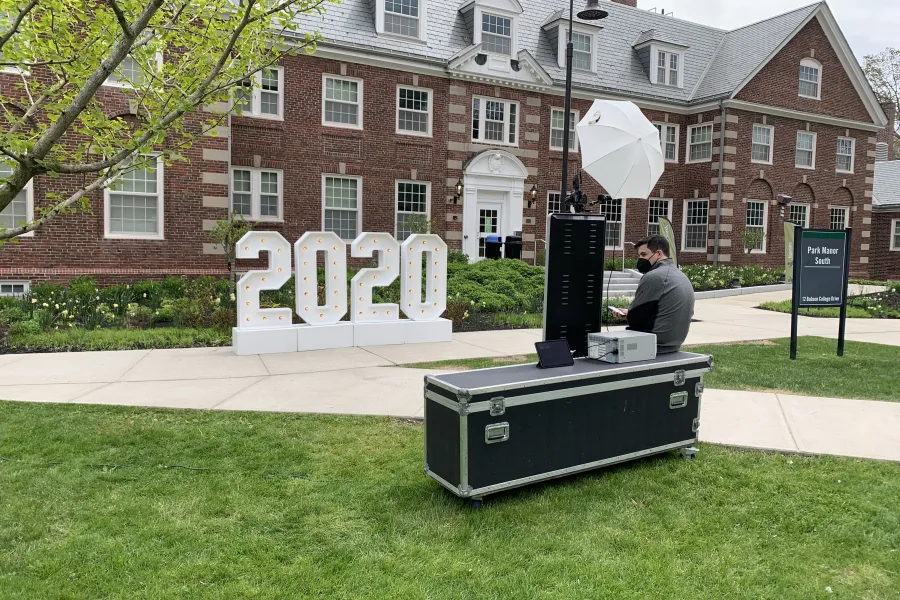 Photo booth set up outdoors on a campus lawn beside graduation letters