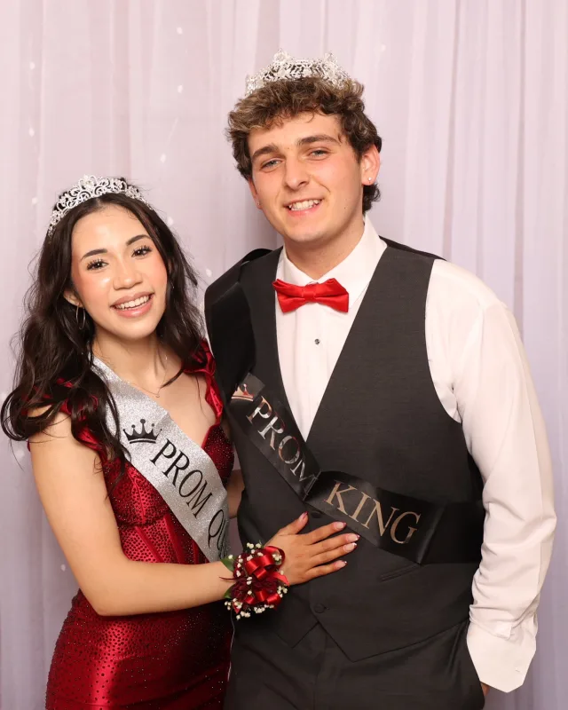 Prom king and queen posing together at a school dance photo op