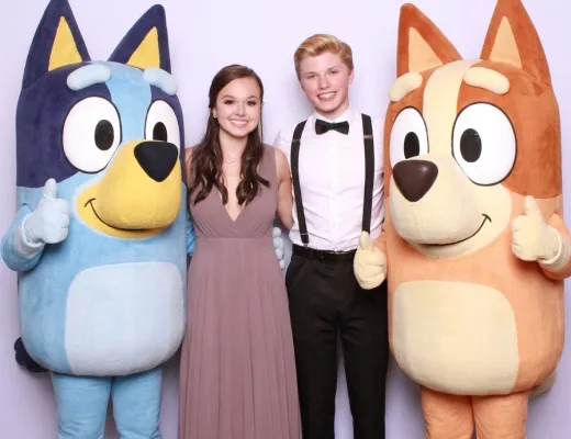 Teen couple posing with two costumed cartoon characters at a formal event photo op