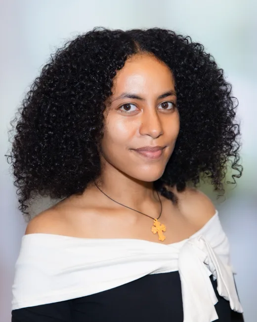 Corporate headshot of a woman with natural curls on a neutral backdrop