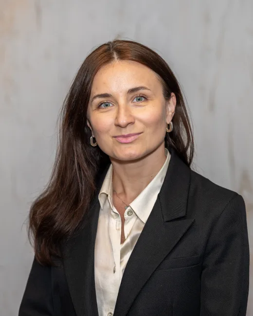 Executive headshot of a woman in a dark suit against a stone backdrop