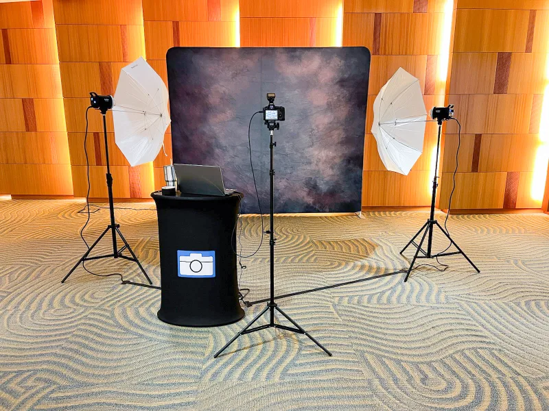 Professional headshot setup with tripod camera backdrop strobe flash heads and laptops on location