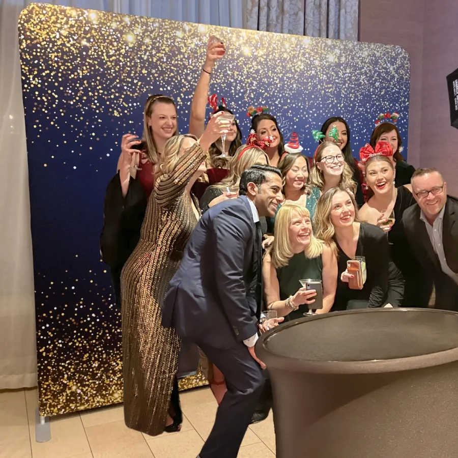 Group of guests cheering at a holiday party photo booth backdrop