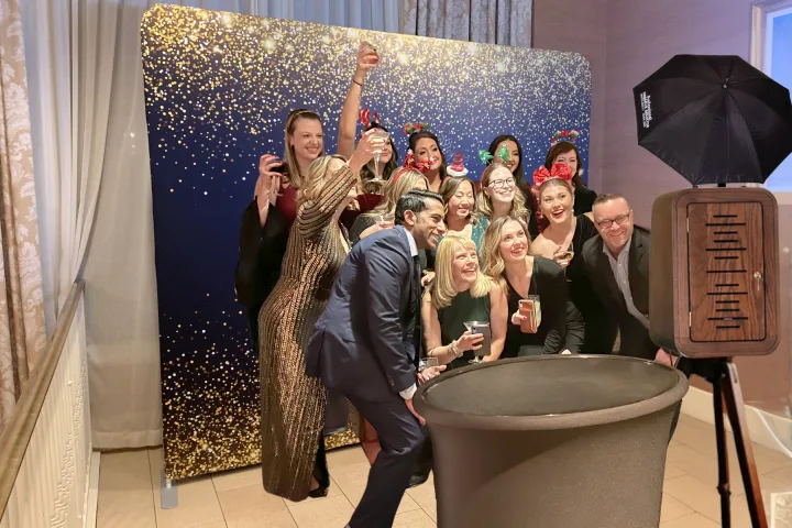 Group of guests toasting at a holiday party photo booth backdrop