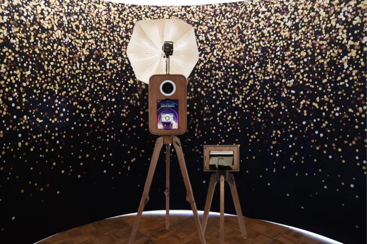 Flashback booth and printer in front of a gold confetti backdrop