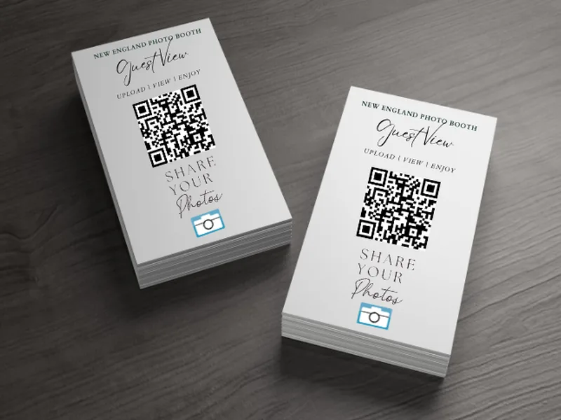 Branded GuestView QR code cards on an event table for guests to scan and join the gallery