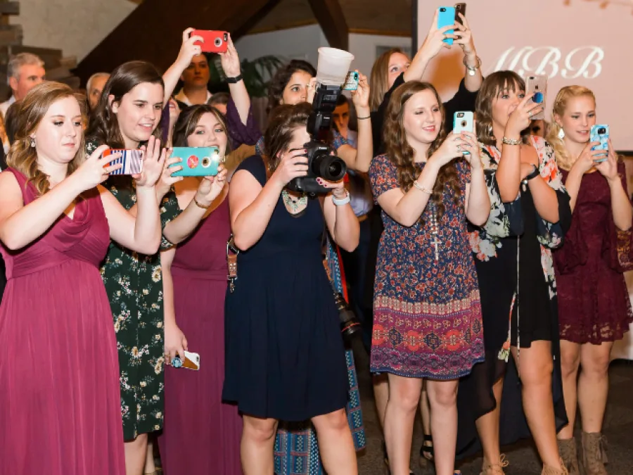 Wedding guests holding up their phones, all taking photos of the same moment