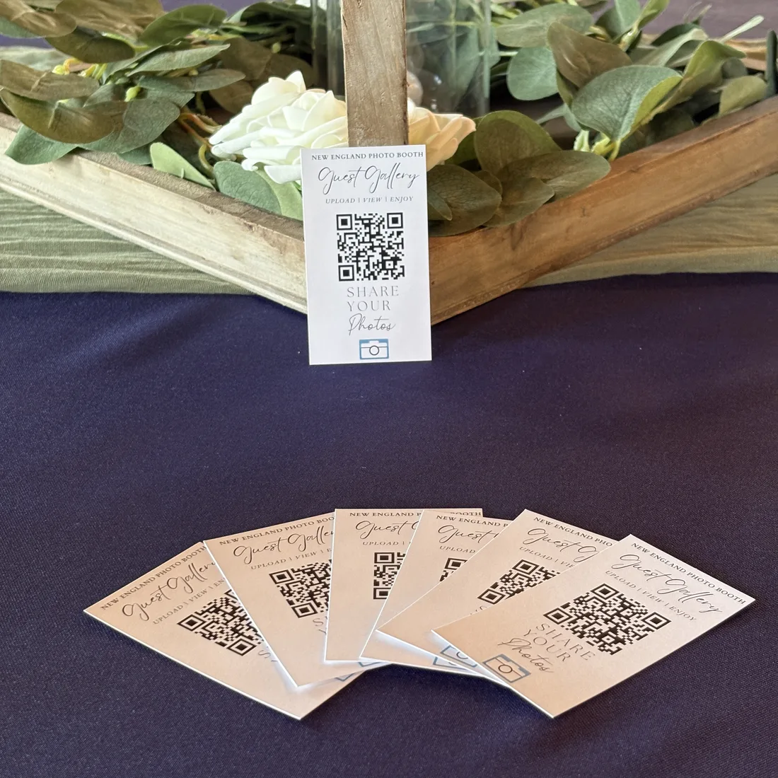 GuestView Guest Gallery QR cards on a navy table with greenery