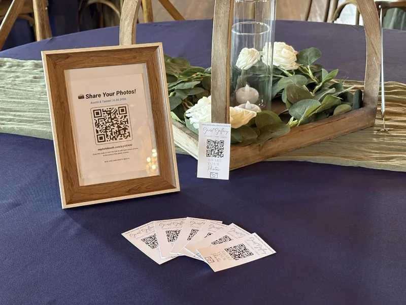 GuestView branded QR table sign and Guest Gallery cards styled on a wedding reception table