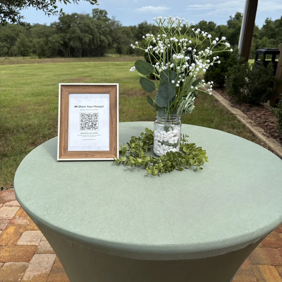 GuestView framed QR sign on an outdoor cocktail table with florals