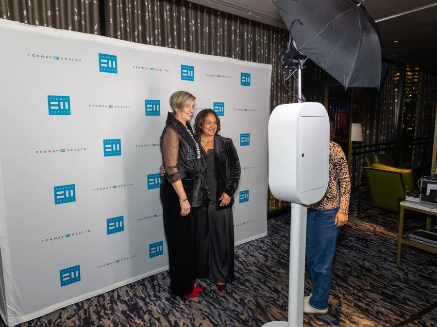The LuxPod photo booth in front of a branded step-and-repeat at a corporate event