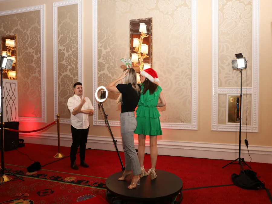 Guests in Santa hats on the 360 booth platform at a company holiday party in a hotel ballroom