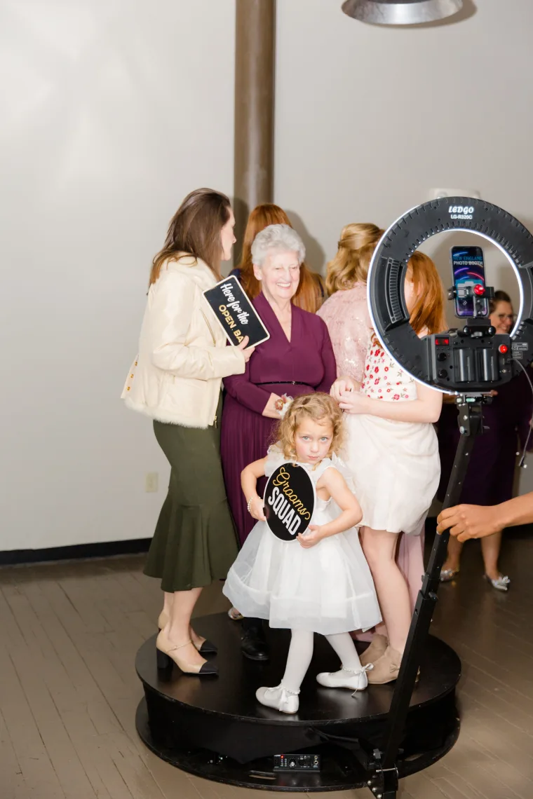 Grandmother and flower girl holding a prop sign at the 360 booth