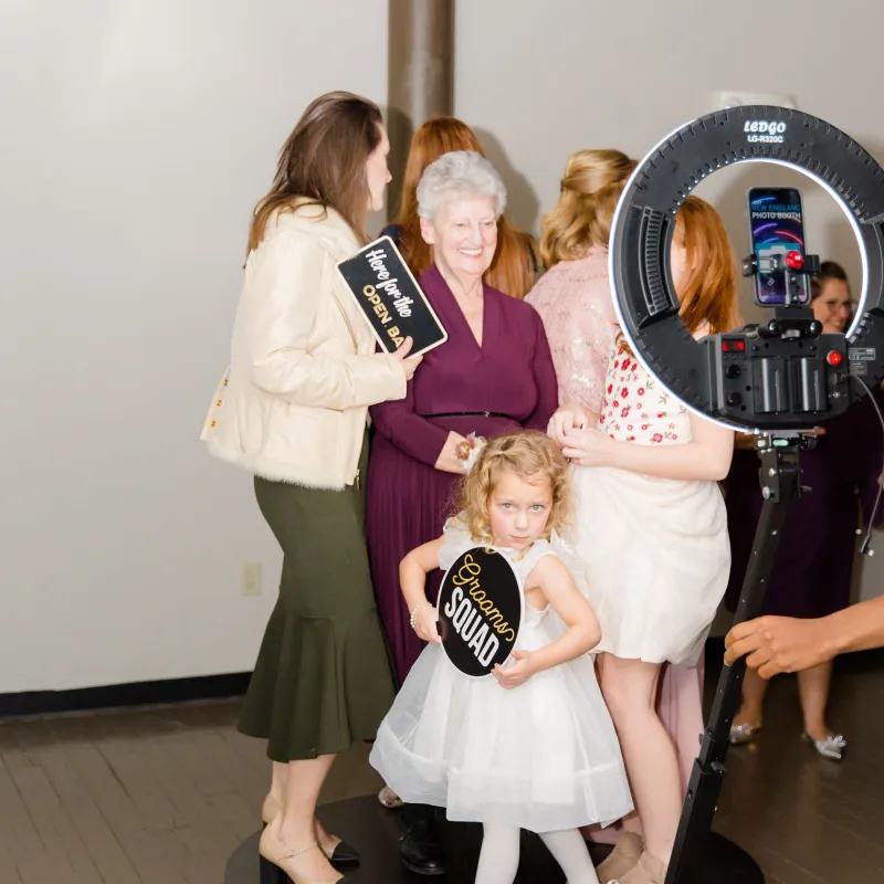 Three generations of a family holding props at the 360 booth ring light