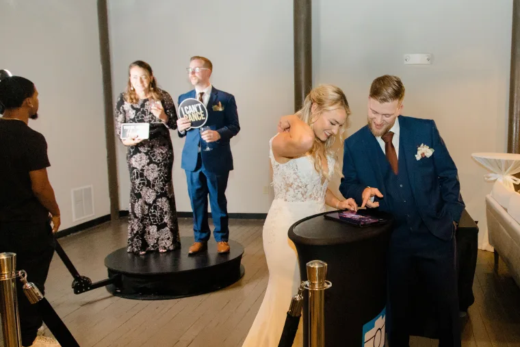 Bride and groom holding a prop sign on the 360 video booth