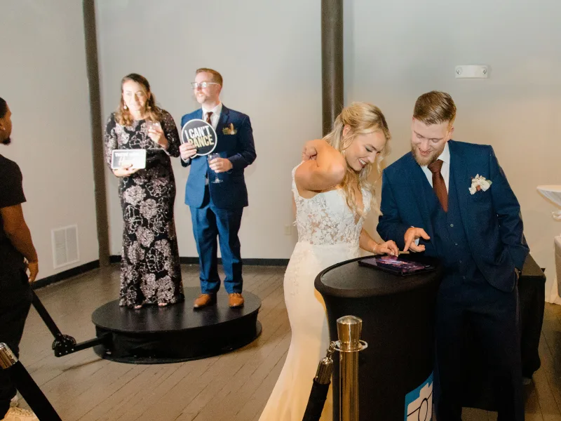 Bride and groom holding a wedding prop sign on the 360 booth