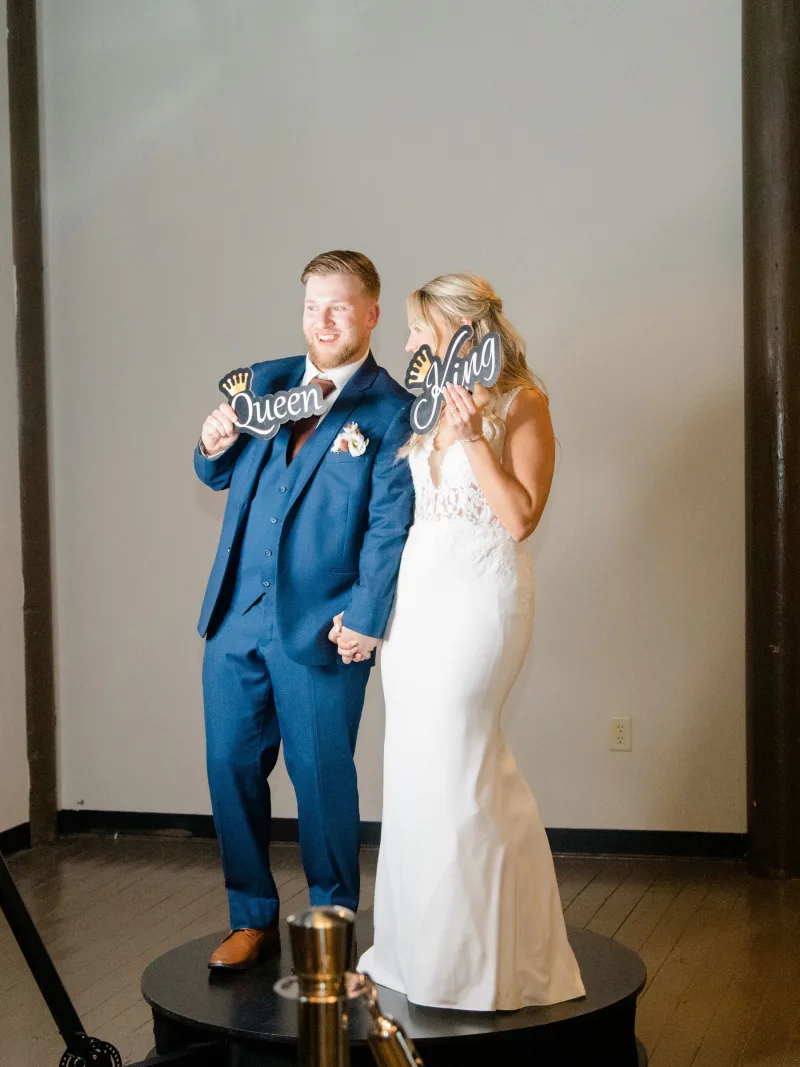Bride and groom holding a prop sign on the 360 video booth platform