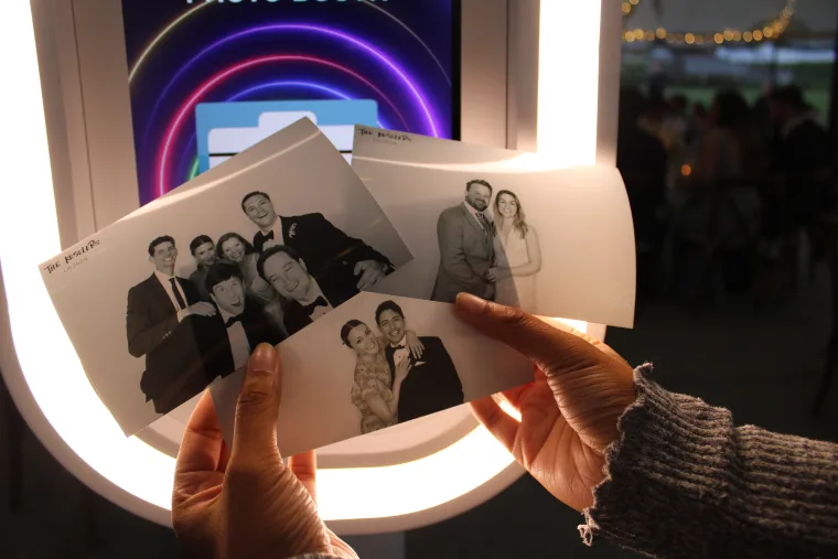 Guest holding fresh black-and-white photo booth prints at the LuxPod