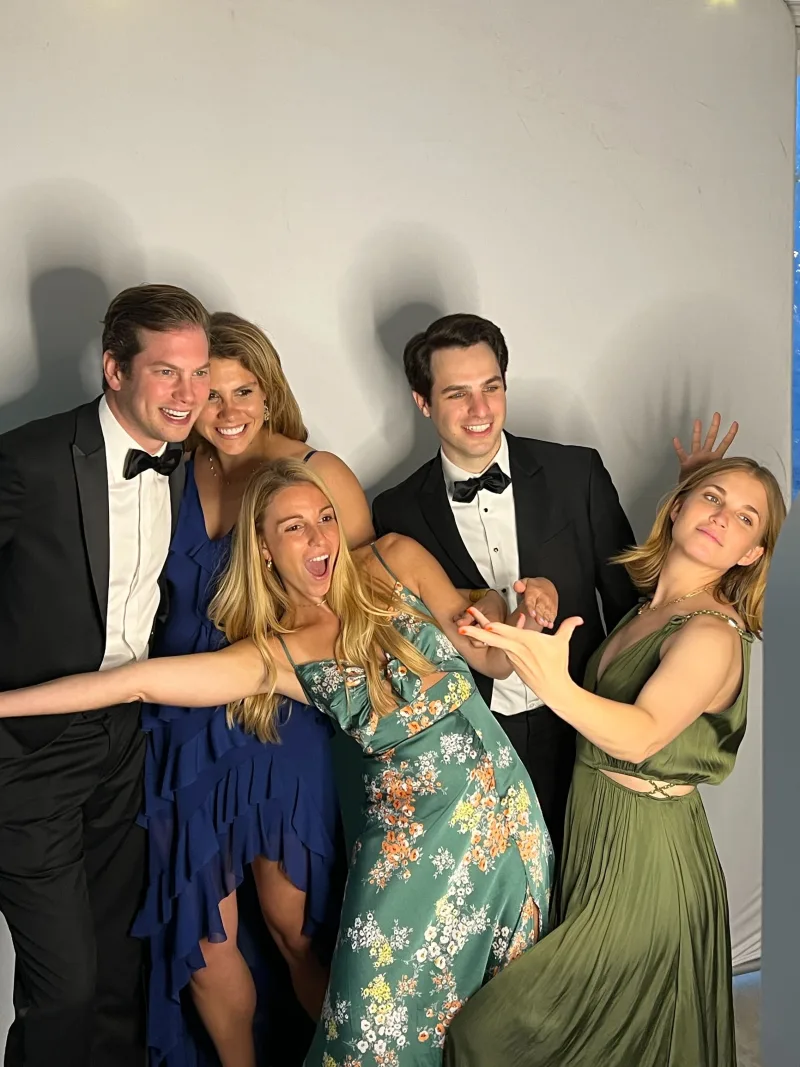 A bridal party in black tie posing with the LuxPod photo booth under a wedding tent