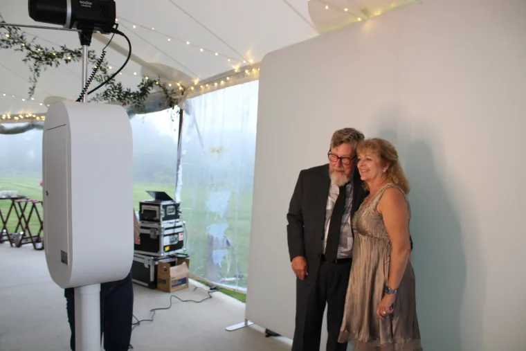 Couple posing with the LuxPod photo booth at a tented reception
