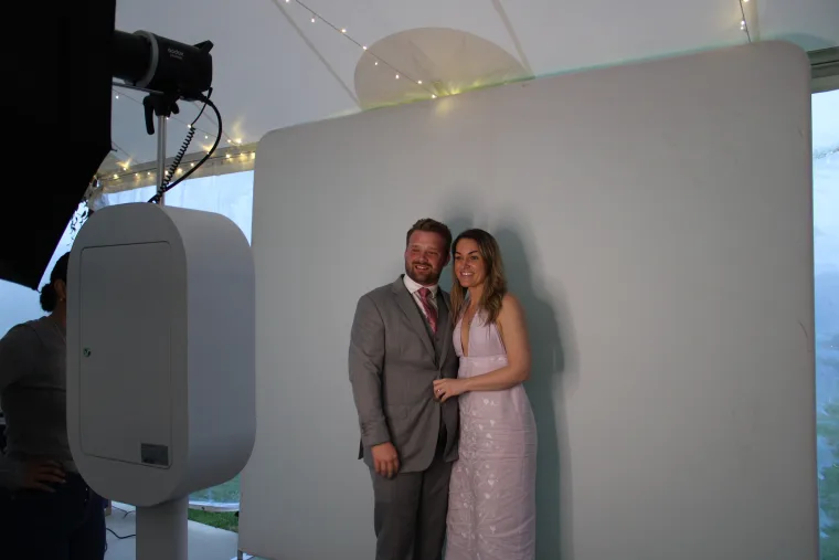 Couple in a grey suit and blush dress posing at the LuxPod under a tent