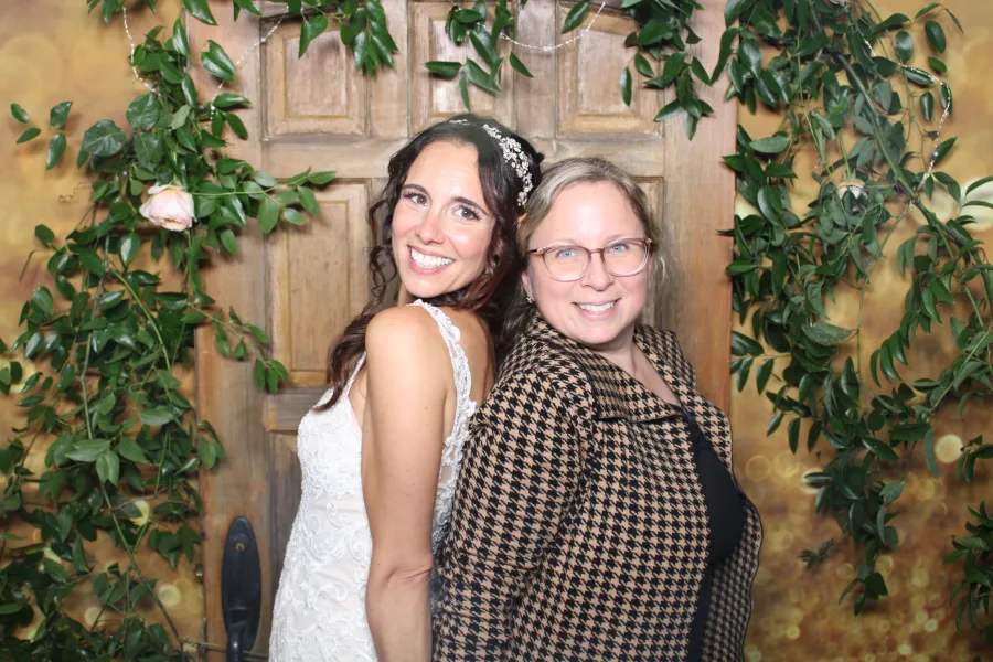 Two guests photographed in a greenery arch and rustic door set