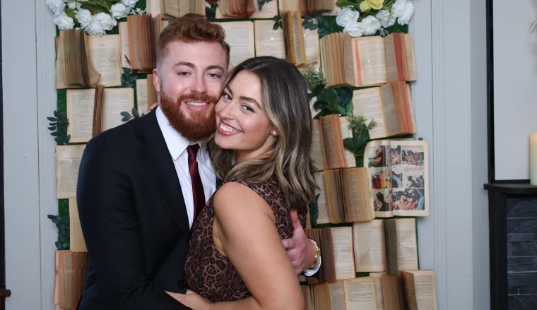 Couple posing in front of a vintage bookshelf backdrop