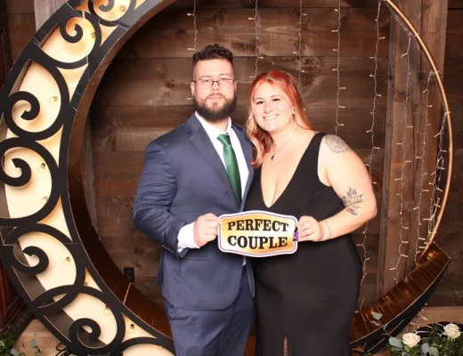 Couple holding a Perfect Couple sign inside a lit crescent moon set