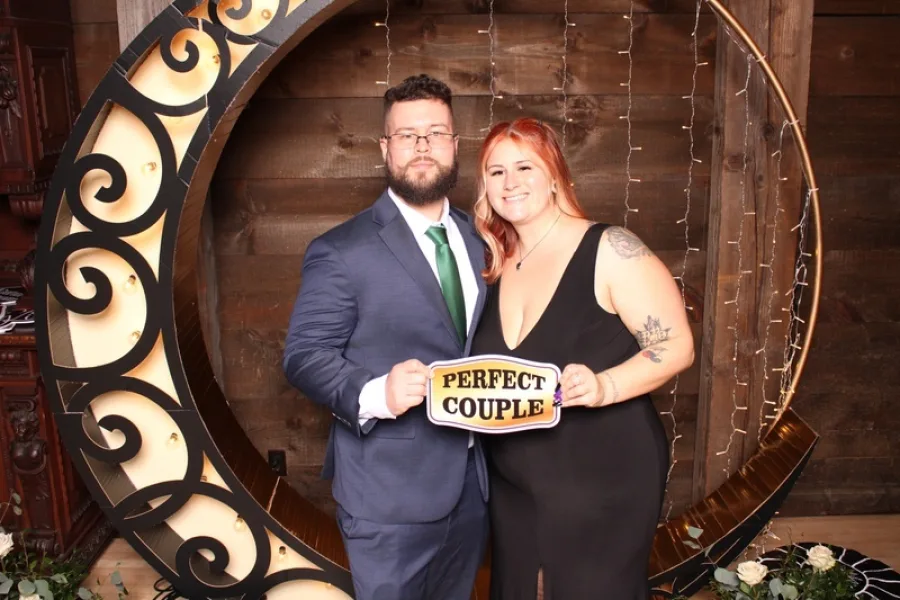 Couple holding a Perfect Couple sign inside a lit crescent moon set