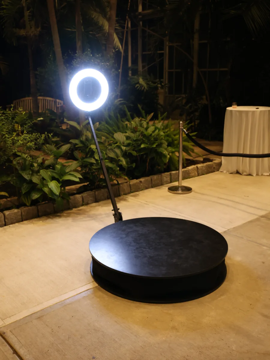 The 360 booth platform with its ring light lit in a garden atrium at night