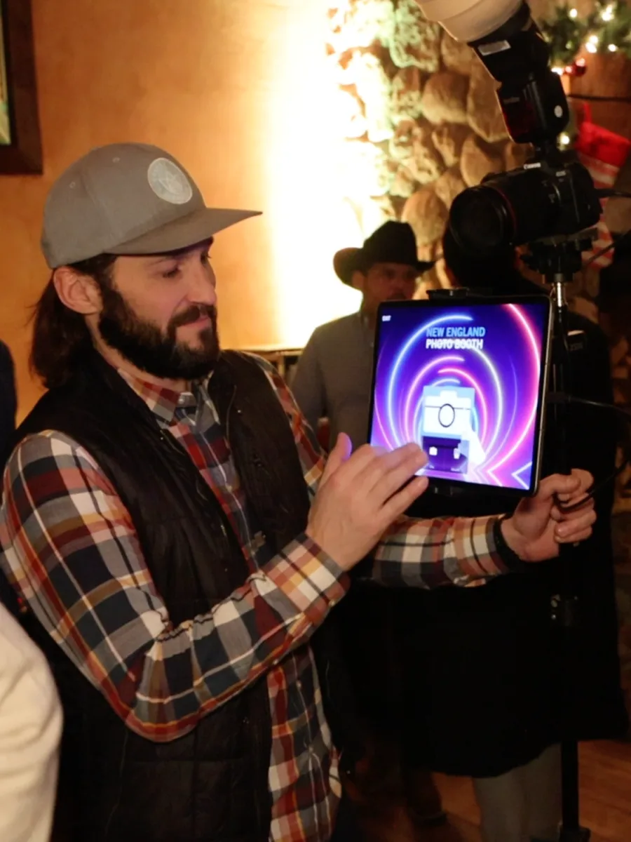 An attendant holding the Roaming Booth rig with its screen lit at an event