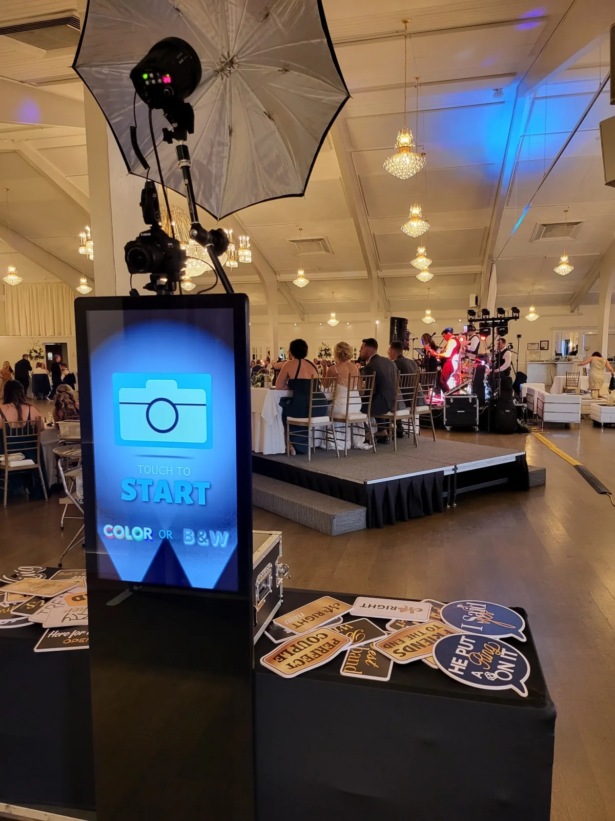 The Open Air Photo Tower with its touch screen lit and a table of prop signs at a ballroom event